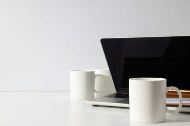 Dizüstü bilgisayarlı beyaz bardaklar.
