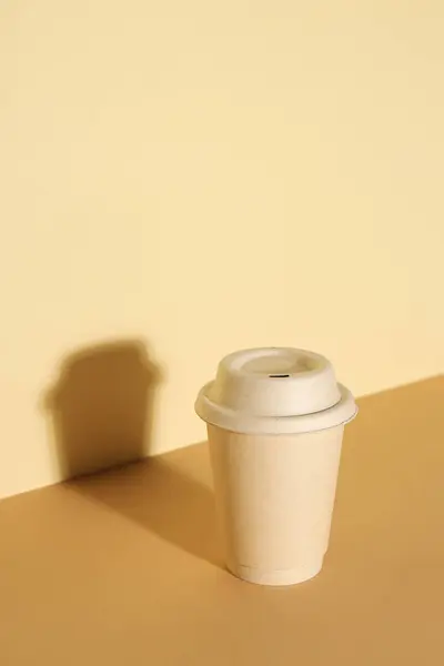 A paper cup with a lid on a light background