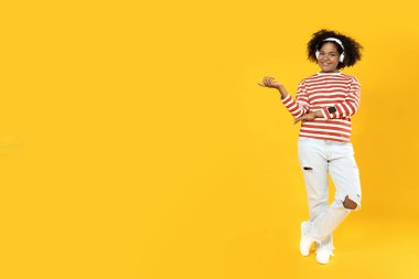 Genç Afrikalı Amerikalı kadın kulaklıkla müzik dinliyor.