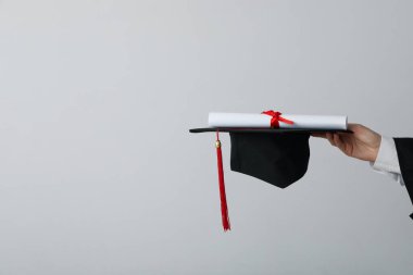 Gri arkaplanlı üniversite mezunu şapkası ve diploması..