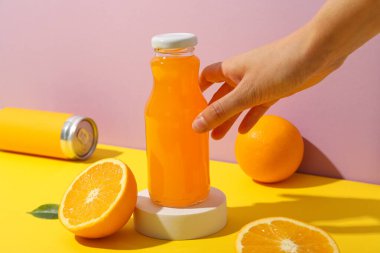 Meyve suyu, portakal suyu ve pembe arka planda bir cam şişe.