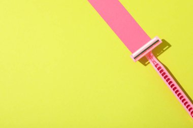 Sarı arka planda tıraş olmak için pembe jilet.