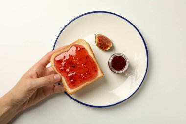 Beyaz arka planda incir reçeli, tabak ve tost ekmeği, üst manzara.