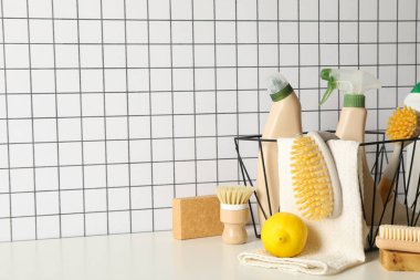 Havlulu sepet ve deterjan şişeleri, fırçalar ve arka planda limon, metin için yer