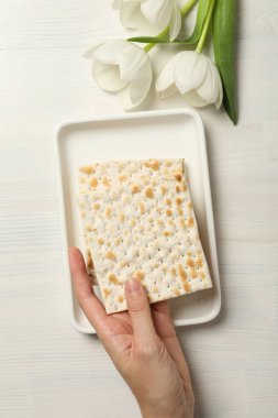 Matzo tabakta, el ve çiçek beyaz ahşap arka planda, üst manzara