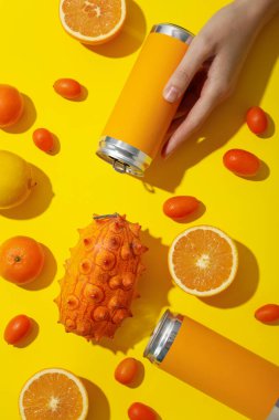 Sarı arka planda tropikal meyve ve teneke kutular, üst manzara