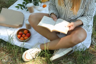 Pikniğe giden bir kız kitap okuyor.