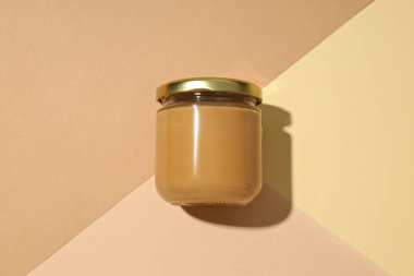 Cam bir kavanozda, arka planda fıstık ezmesi..