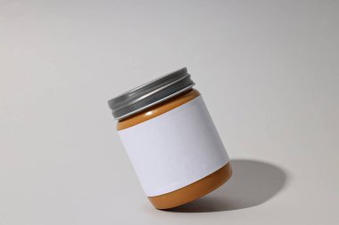 Gri arka planda etiketli kavanoza fıstık ezmesi..