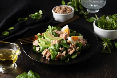 Karanlık bir masada çatallı ton balıklı salata..