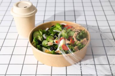 Işık masasındaki karton tabakta ton balığı salatası..