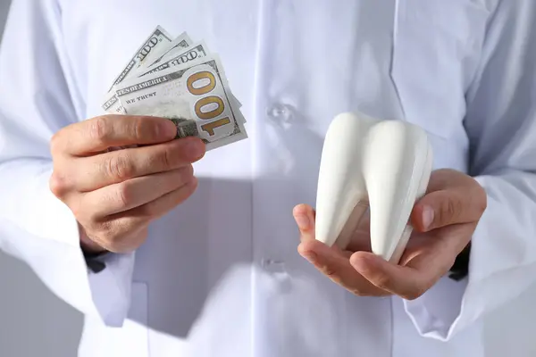 灰背牙医手中的美元和牙齿 — 图库照片