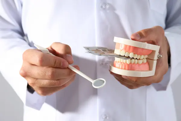 浅色背景的牙医手拿着牙科器械和牙龈 — 图库照片