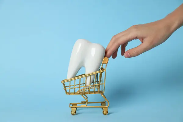ショッピングカートの歯と青の背景に手 — ストック写真