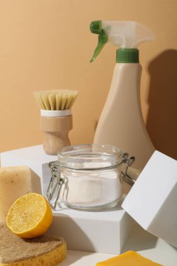 Doğal deterjanlar, sprey şişesi ve bej arka planda temizlik aletleri