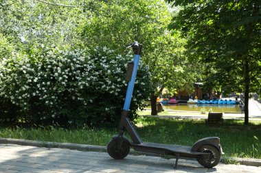 Yasemin çalılığı, scooter, yürüyüş yolu ve göl yazın parkta.