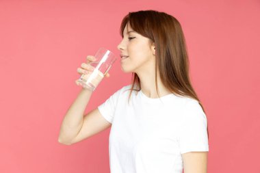 Elinde bir bardak suyla çekici bir genç kız.