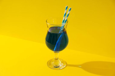 Sarı arka planda pipetli mavi kokteyl