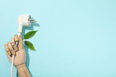 Mavi arka planda mankenin elindeki elektrik kablosu