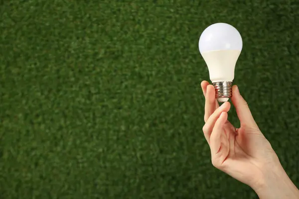 A light bulb in a hand on a background of grass