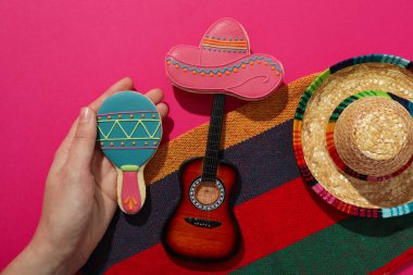 Pembe arka planda dekoratif gitarı olan Meksikalı bir sombrero.