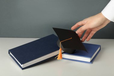 Mezuniyet şapkası ve karanlık bir arkaplanda kitaplar..