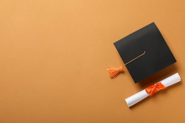 Mezuniyet şapkası ve turuncu arka plan diploması..