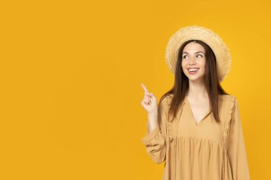 Sarı arka planda şapkalı mutlu genç kadın, mesaj için yer.