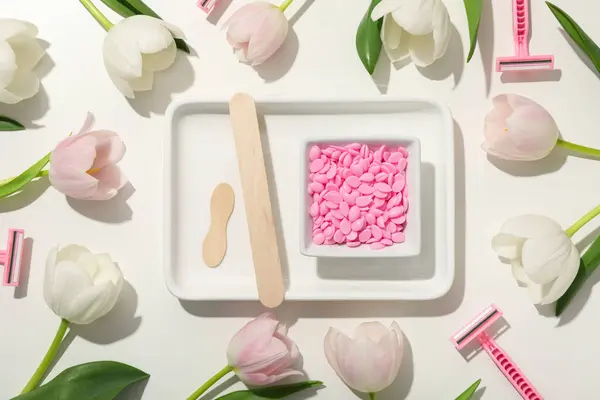 Stock image A white tray with depilatory granules and fresh tulips