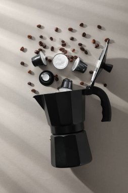 Kahve kapsülleri ve fasulyeler, gri arka planda kahve makinesi, üst manzara.