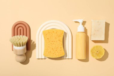 Bej arka planda fırça, sünger ve deterjan, üst görünüm