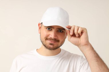 Beyaz tişörtlü, arka planda genç bir adam.