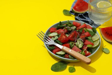 Kasede taze karpuz salatası ve sarı arka planda bir bardak limonata.