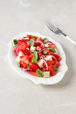 Arka planda bir kasede taze karpuz salatası.