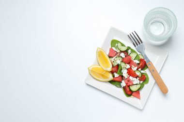 Beyaz arka planda kare bir kasede karpuz salatası.