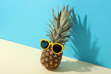 Mavi arka planda sarı güneş gözlüklü ananas