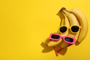 Sarı arkaplanda muz ve güneş gözlüğü, metin için boşluk