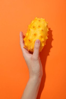 Turuncu arka planda kadın elinde Kiwano meyvesi