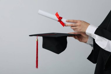 Gri arkaplanlı üniversite mezunu şapkası ve diploması..