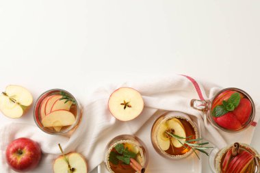 Elma şırası bardakları ve beyaz arka planda havluyla elmalar, metin için boşluk