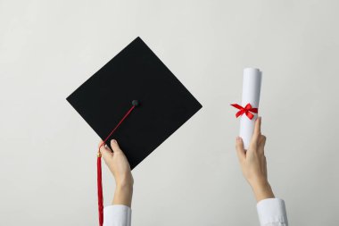 Gri arkaplanlı üniversite mezunu şapkası ve diploması..