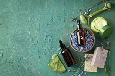 Lavanta, kozmetik ürünü şişeler, sabunlar ve yeşil arka planda yüz masajcıları, mesaj için yer