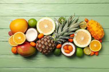 Yeşil ahşap zemin üzerinde tropik meyve seti, üst görünüm