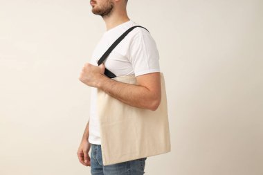 Beyaz tişörtlü, arka planda genç bir adam.