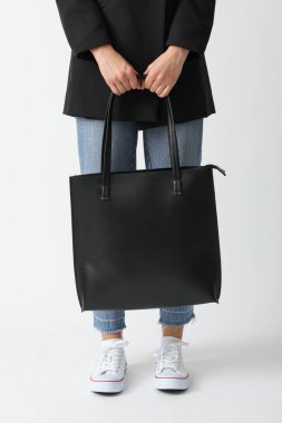 Beyaz arka planda bir kadın çanta tutuyor.