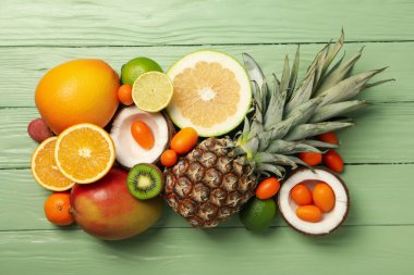 Yeşil ahşap zemin üzerinde tropik meyve seti, üst görünüm