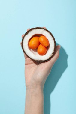 Mavi arka planda hindistan cevizinin yarısında kumkatın tamamı, üst görünümde.