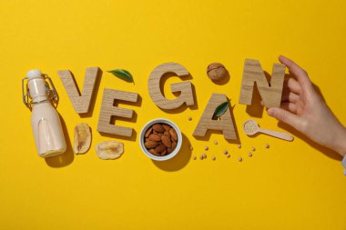 Tahta harfler, bir şişe süt, fındık ve sarı arka plan, üst manzara.