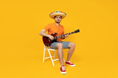 Meksika şapkasıyla gitar çalan çekici genç adam.