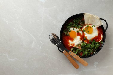 Shakshuka siyah kaselerde, açık arkaplanda.